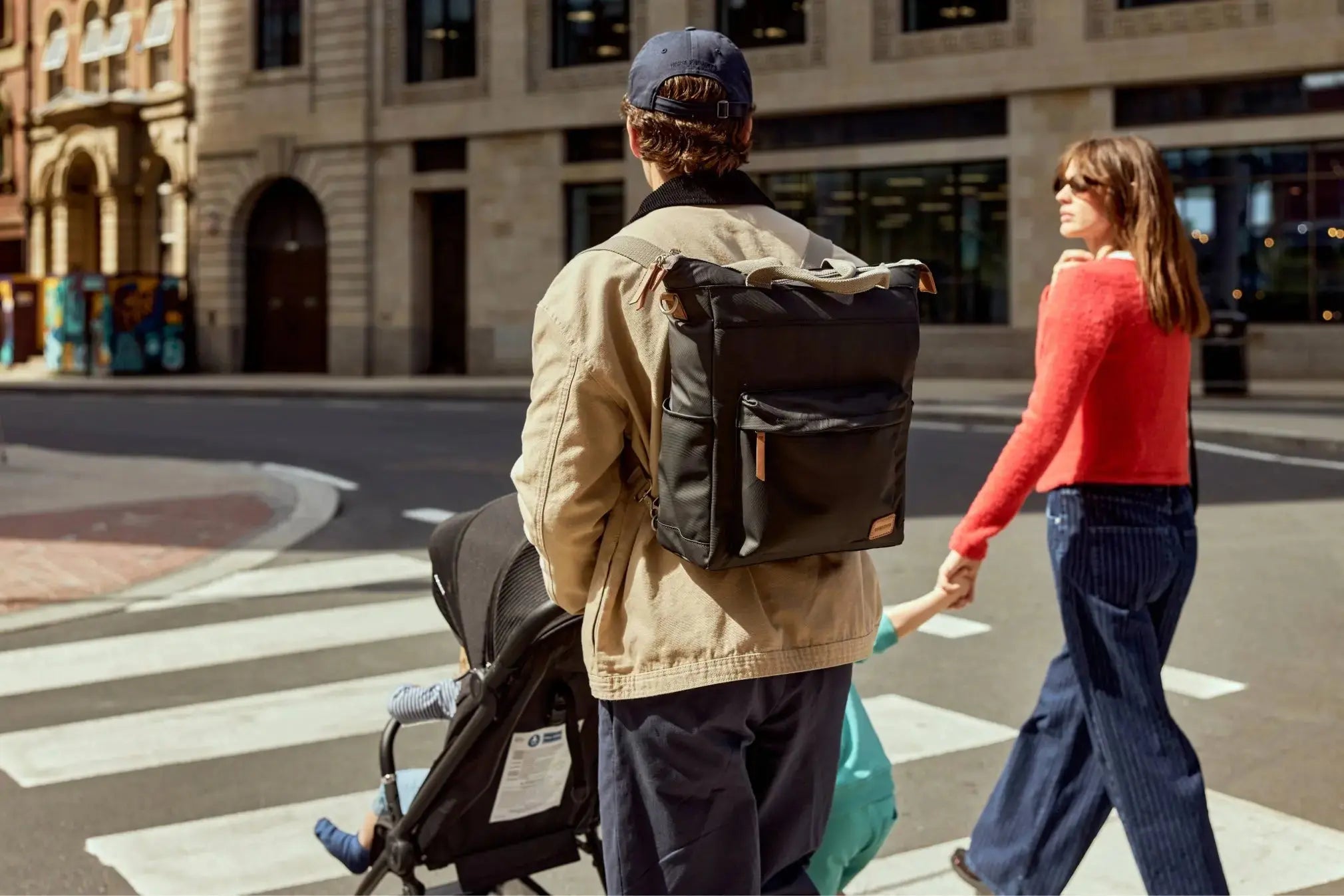 A man wearing a black backpack crossing a zebra crossing