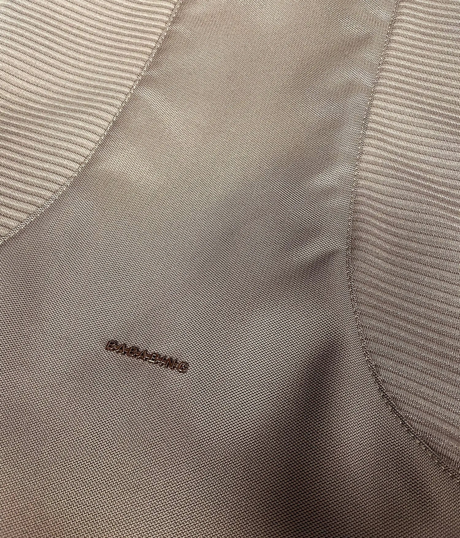 Close-up of a beige fabric with a subtle pattern and brand logo.
