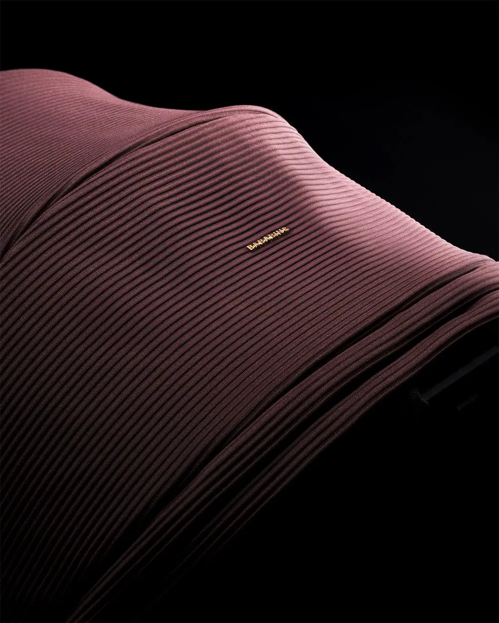 Close-up of a ribbed travel system sun canopy with a brand logo on a black background