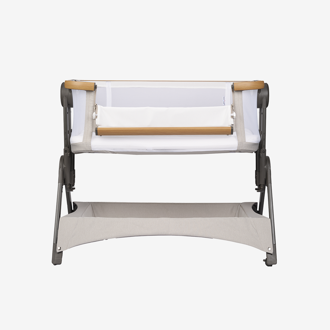 A beige Bababing bedside and travel crib with a wood finish and a soft neutral palette, featuring a white mattress and a Scandinavian-inspired design.